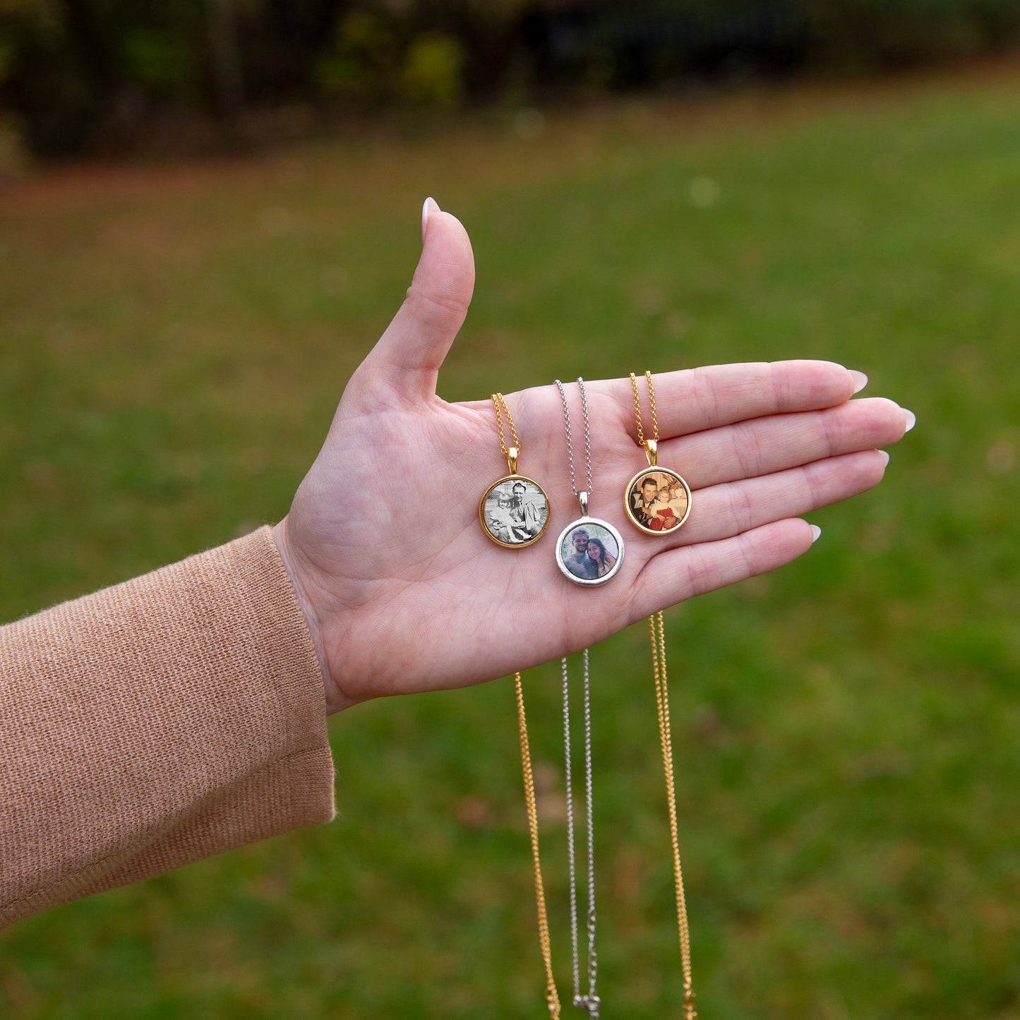 A hand holding three different necklaces.